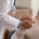 Arzt hält Hand von Patientin, diese lächelt zufrieden.
